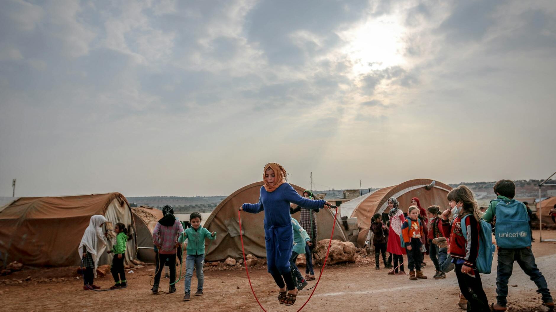 poor ethnic girl with jumping rope among children