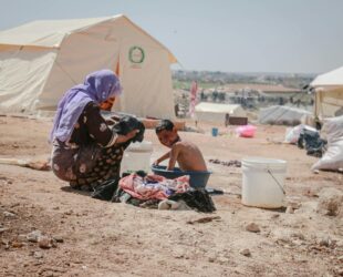 a mother washing a child in a plastic tub