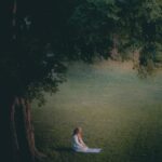 woman in white dress sitting on green grass field