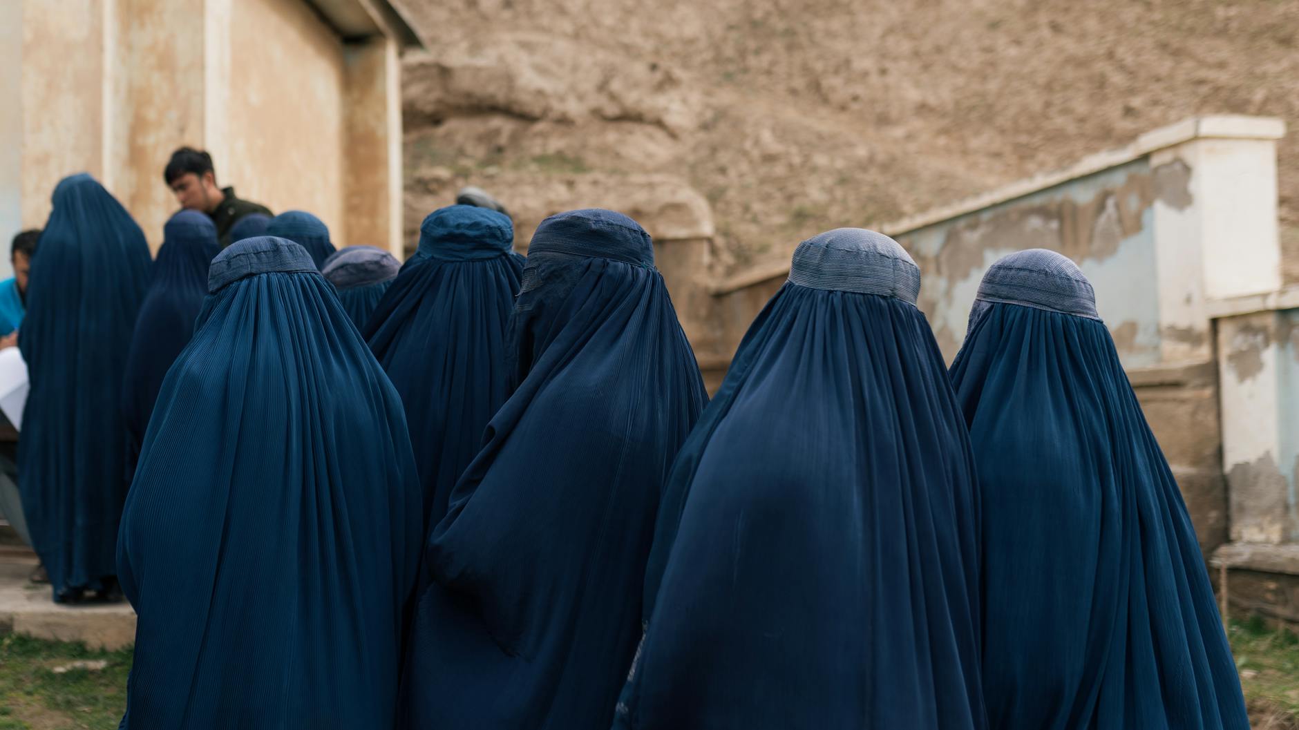 women in blue burqas walking outdoors in afghanistan